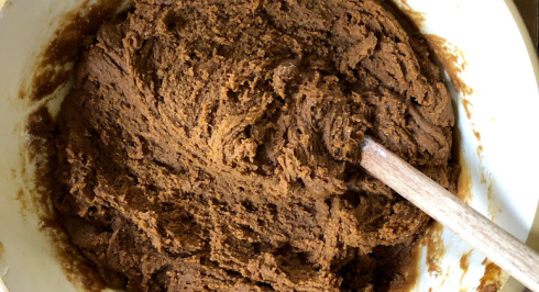 Molasses Cookie batter in a mixing bowl with a wooden spoon.