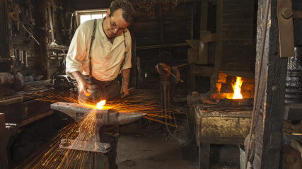 Costumed interpreter, a man working in the Blacksmith at Ross farm.