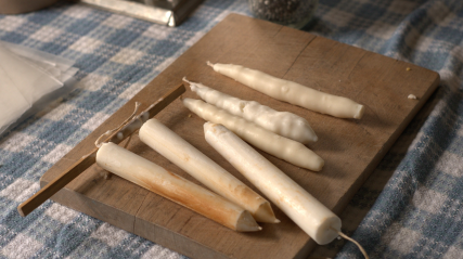 Hand made candles on a wooden board on a table.