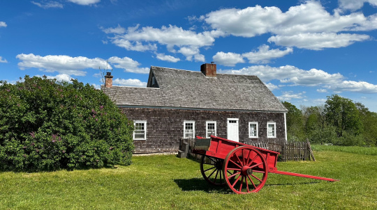 Rosebank cottage, blue sky, red wagon in front.